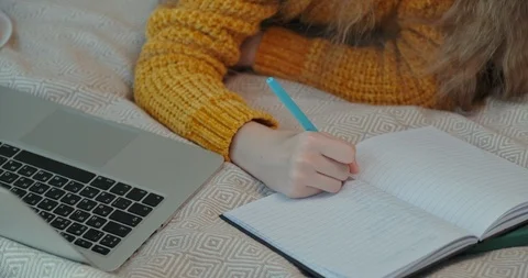 Young student something writing in exercise book  and lying on bed Stock Footage 127249558