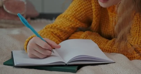 Young student something writing in exercise book, when she lying on the bed Stock Footage 127322241