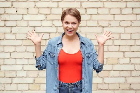 Young student standing isolated on wall hands aside smiling playful Stock Photos