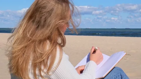 Young student study with notebook on beach next to sea ocean view. Writing Stock Footage 220534677