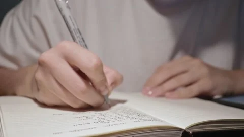 Young student studying, doing homework in notebook, using pen on white paper Stock Footage 163251733