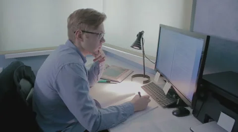 Young student studying in front of his computer and taking notes Video stock 59958441