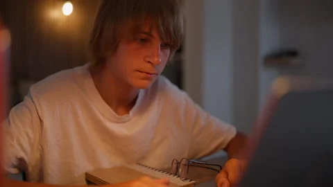 Young student studying independently at home using a laptop and notebook. I.. Stock Footage 341976739