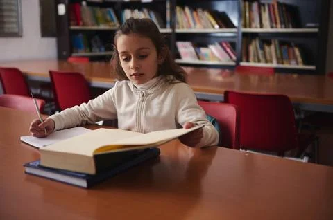 Young Student Studying in Library With Large Open Book and Notes Foto stock