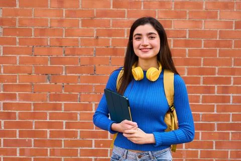 Young student with tablet standing by brick wall Stock Photos