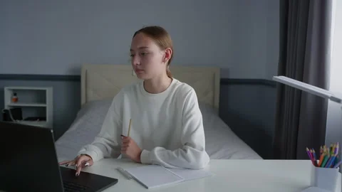 Young student taking notes while studying on laptop in bedroom Stock Footage 315174932
