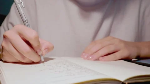 Young student with tender hands use black pen to write thoughts in daily journal Stock Footage 163251782