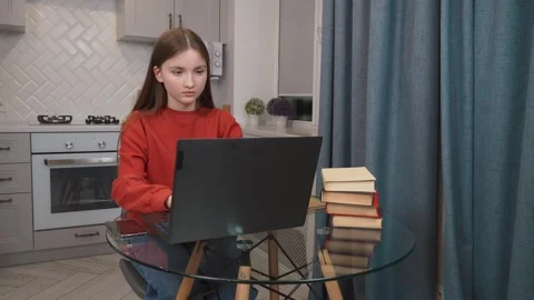 Young student typing on laptop with stack of books Stock Footage 311780090