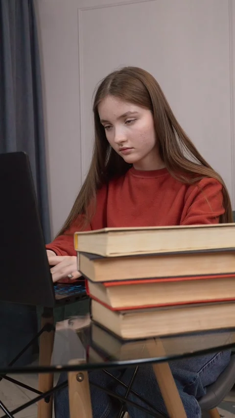 Young student typing on laptop with stack of books Stock Footage 311813266