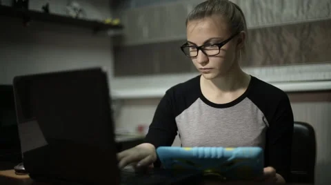 Young student uses a laptop and a tablet at night Video stock 60051968