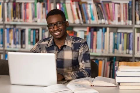 Young Student Using His Laptop In A Library Stock Photos