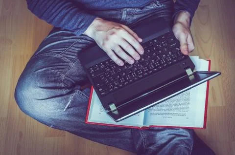 Young student using a laptop and sitting on the wooden floor in a classroom Stock Photos
