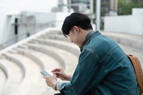 Young Student Using mobile Outdoors on Campus Steps, Casual Lifestyle, Modern Stock Photos