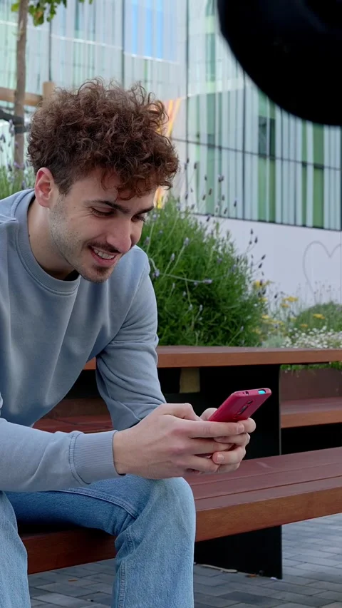 Young student using mobile phone while sitting on table at campus college. Stock Footage 277960288