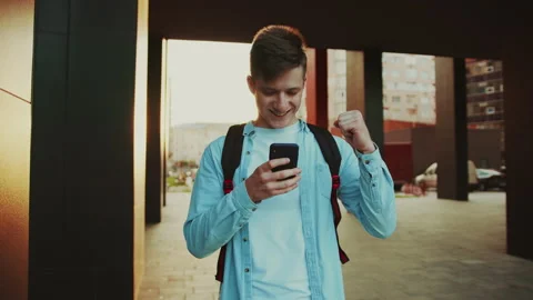 Young student using smartphone and raised fist up like a winner. Portrait of Stock Footage 141557798