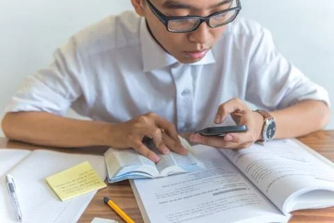 Young student using smartphone and doing homework Stock Photos