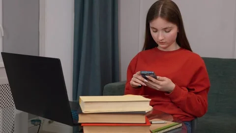 Young student using smartphone while studying at home Stock Footage 311780758