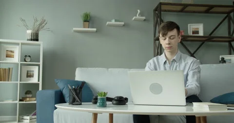 A young student works at a computer at home in a cozy atmosphere, puts on Stock Footage 132033834