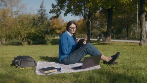 Young student writes in notebook in a scenic autumn park Stock Footage 300264080