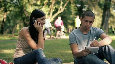 Young students with cellphone and notebook in the park, steadicam shot HD Stock Footage