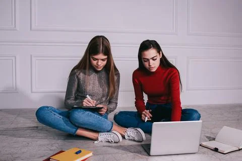 Young students doing homework together sitting on floor Stock Photos
