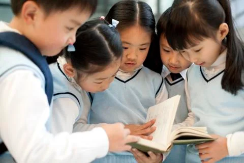 Young students huddle together reading a book Stock Photos