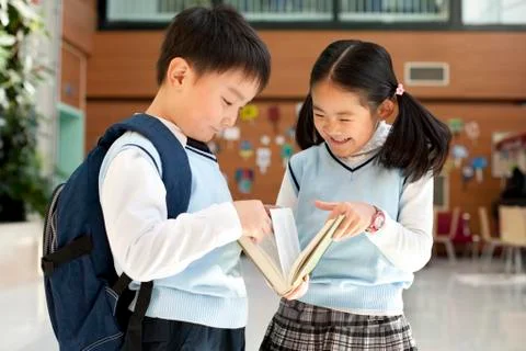 Young students huddle together reading a book Stock Photos