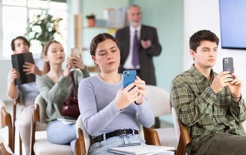 Young students scanning QR-code with mobile devices during presentation Foto stock