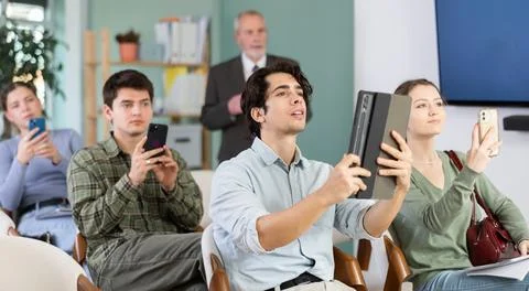 Young students scanning QR-code with mobile devices during presentation Stock Photos