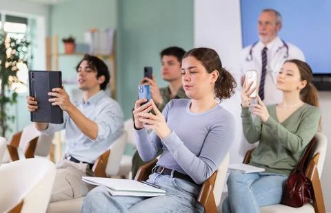 Young students scanning QR-code with mobile devices during presentation Stock Photos