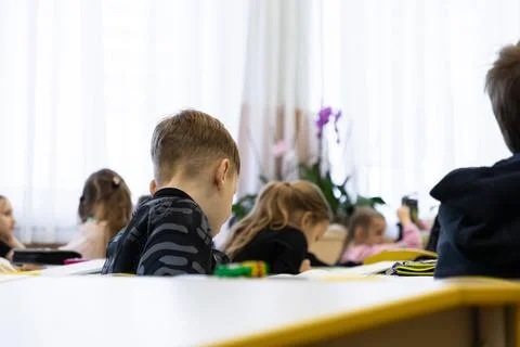 Young students sit at desks in an elementary school classroom focusing on t.. Stock Photos