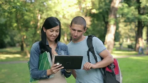 Young students with tablet computer in the park, steadicam shot HD Stock Footage 12015206