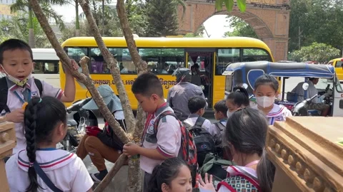 Young students in uniform playing and talking near street Poipet border Stock Footage 252556535