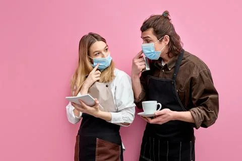 Young students work as waiters, stand having conversation during work Stock Photos