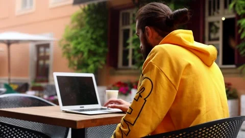 Young stylish attractive man using laptop sitting in cafe outside enjoying conne Video stock 132259256