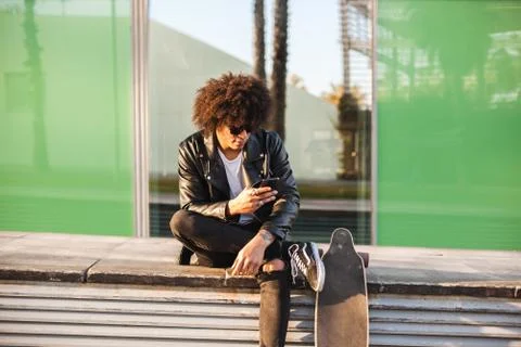 Young stylish black man using smart phone in sunny city Stock Photos