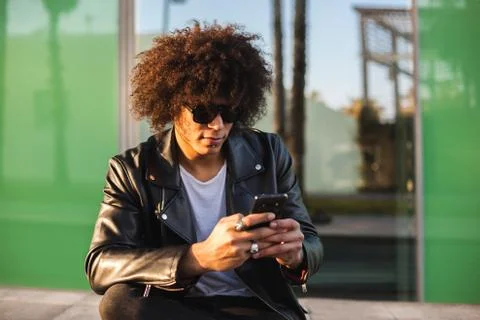 Young stylish black man using smart phone in sunny city Stock Photos