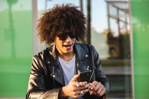Young stylish black man using smart phone in sunny city Stock Photos