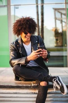 Young stylish black man using smart phone in sunny city Stock Photos