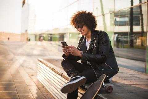 Young stylish black man using smart phone in sunny city Stock Photos