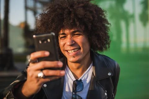 Young stylish black man using smart phone in sunny city Stock Photos