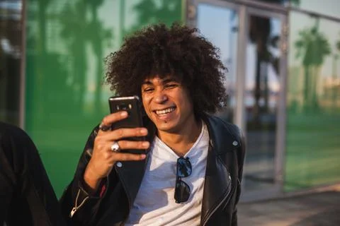 Young stylish black man using smart phone in sunny city Stock Photos