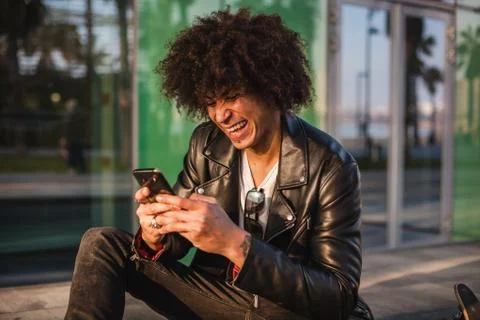 Young stylish black man using smart phone in sunny city Stock Photos