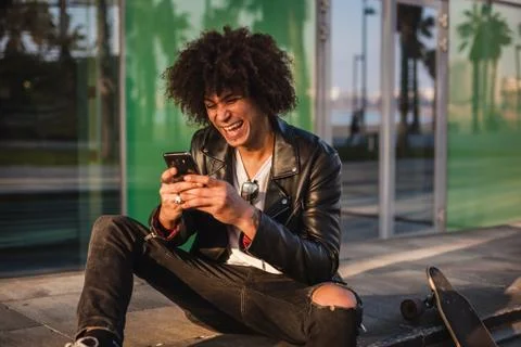 Young stylish black man using smart phone in sunny city 写真素材