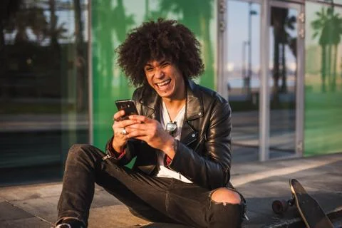 Young stylish black man using smart phone in sunny city Stock Photos