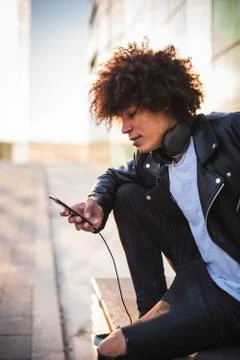 Young stylish black man using smart phone in sunny city Stock Photos
