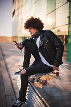 Young stylish black man using smart phone in sunny city Stock Photos