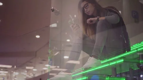 Young stylish brunette sits on a luminous green staircase and uses a smartphone Stock Footage 83620191