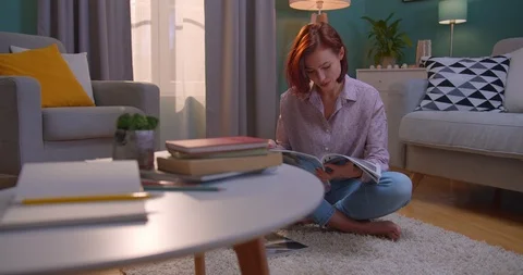 Young stylish charming red-haired woman reading a fashion magazine o the floor Stock Footage 122498929