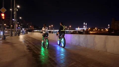 A young stylish couple rides on bicycles with flashing multicolored wheels. Vídeo Stock 130481908
